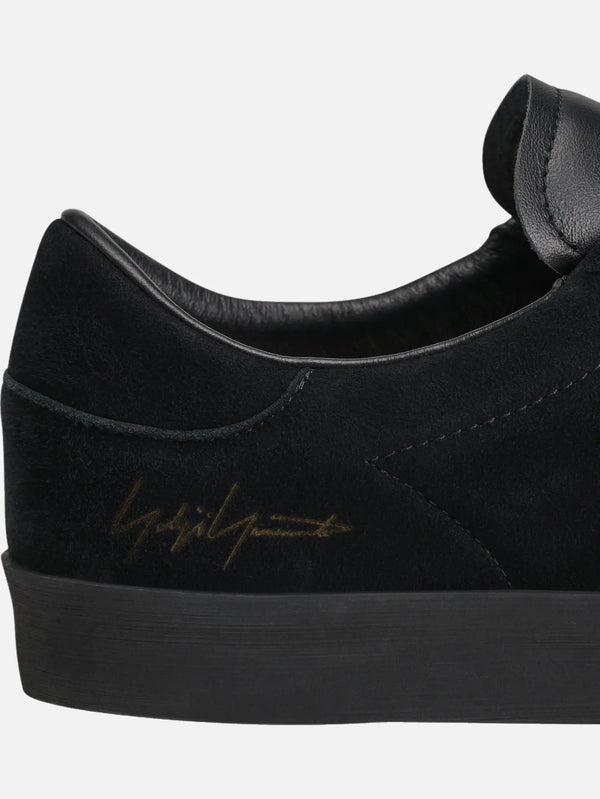 Y-3 Gazelle – Triple Black, yakın çekim, siyah süet üst ve arka altın logo detayı
