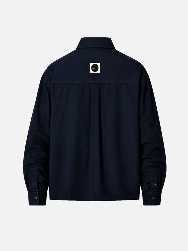 shopi go Meguro Regular Shirt – Navy, arka görünümde orta üstte beyaz kare rozet ve siyah daire